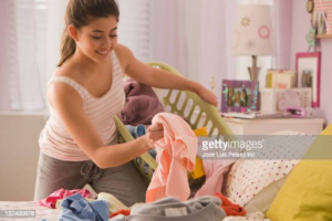 young lady putting away clothes into laundry basket
